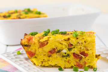 Breakfast casserole with bacon, potatoes, vegetables.