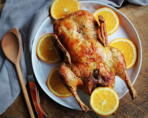 Whole crispy golden roast duck with marinated with fresh orange slices for a festive . Top view rustic wooden background.