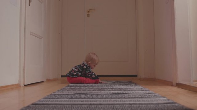 Cute little baby boy in christmas sweater crawling on the floor playing with drawing paper looking around at home interior. Family concept.