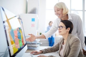 Side view portrait of two businesswomen using computer in design agency