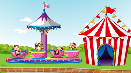 Scene with cute monkeys riding on spinning cup in the park