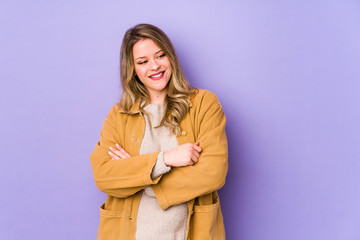 Young caucasian woman isolated on purple background smiling confident with crossed arms.