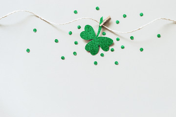 St. Patricks day background with Homemade glitter shamrocks garland. Shiny paper cut clover leaf on...