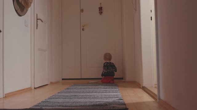 Toddler cute little boy in Christmas sweater crawling on floor in the corridor at home. Babies and childhood concept.