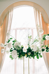 floral decoration of wedding tables, delicate white flowers and branches of fresh greenery on white hall