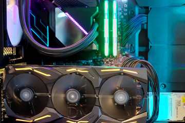 Close-up and inside Desktop PC Gaming and Cooling Fan CPU system with multicolored LED RGB light show status on working mode, interior DIY PC Case, selective focus at Computer Graphic Card