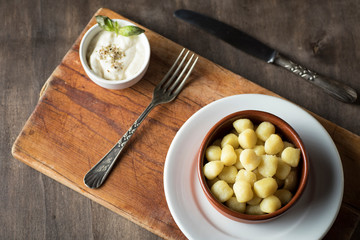 Delicious dish of round potato gnocchi accompanied by cheese sauce with the necessary accessories to taste them