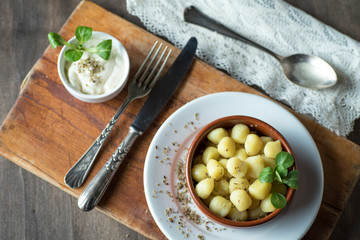 Delicious dish of round potato gnocchi accompanied by cheese sauce with the necessary accessories to taste them