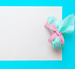 Egg gift in green paper packaging and with pink ribbon Easter Bunny wrap idea. Chocolate dragee...