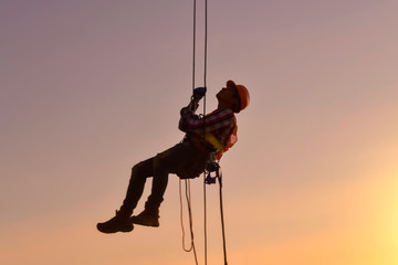 Construction worker wearing safety work at high uniform on scaffolding at construction site on...