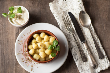 Delicious dish of round potato gnocchi accompanied by cheese sauce with the necessary accessories to taste them