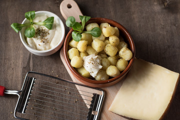 Delicious dish of round potato gnocchi accompanied by cheese sauce with the necessary accessories to taste them