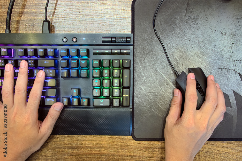 Poster close-up hands of gamer who use mechanical gaming keyboard and gaming mouse for play game on compute