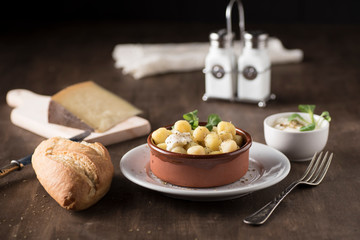 Delicious dish of round potato gnocchi accompanied by cheese sauce with the necessary accessories to taste them
