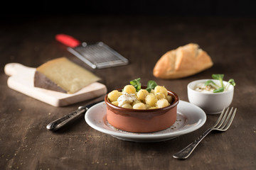 Delicious dish of round potato gnocchi accompanied by cheese sauce with the necessary accessories to taste them