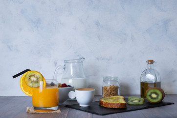 Complete breakfast consisting of coffee with milk, orange juice, fresh fruit, cereals and corn bread toast with olive oil on a wooden surface. Healthy concept.