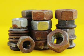 Piles of old rusty nuts different sizes, on a yellow background. Macro photography.