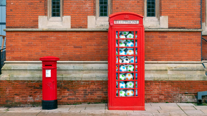 Royal Shakespeare Theatre, Stratford upon Avon, England, UK close view of one of the building walls, with an iconic red post box and a phone both filled with footballs in front