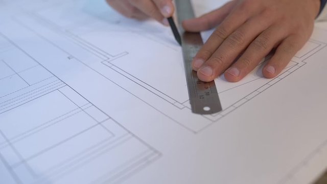 Professional draftsman working on project of construction, drawing by pencil