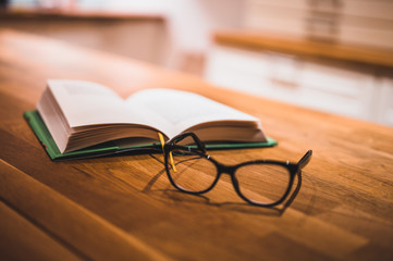 Open book and glasses on table. Book and glasses.