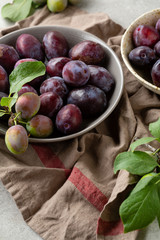 Close up of Fresh plums in bowls on rustic cloth