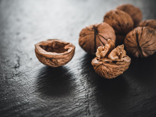 Whole walnuts on dark board. Walnut kernels on dark background. Healthy food nuts.