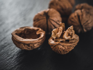 Whole walnuts on dark board. Walnut kernels on dark background. Healthy food nuts.