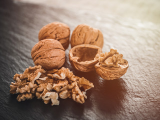 Whole walnuts on dark board. Walnut kernels on dark background. Healthy food nuts.