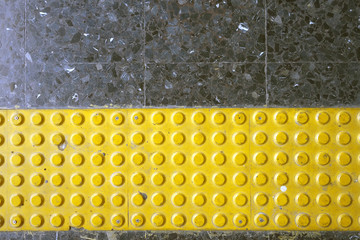 yellow braille block on dark granite tile floor