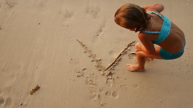 Child draws on the sand.