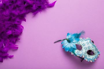 Purple feather boa with blue carnival mask and copy space
