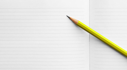 simple yellow pencil on a spread of blank pages of a school notebook, concept back to school, study term start