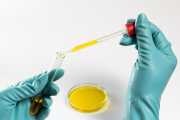  scientist laboratory testing lab dropper with yellow fluid test in petri dish