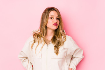 Young caucasian woman isolated on pink background sad, serious face, feeling miserable and displeased.