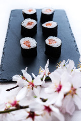Stock photo of Sakura flower with sushi background on a black slate tray all on a white background.