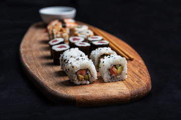 Foto de stock de composición de sushi con Maki, California Roll y Nigiri con palillos y salsa de soja sobre tabla de madera.