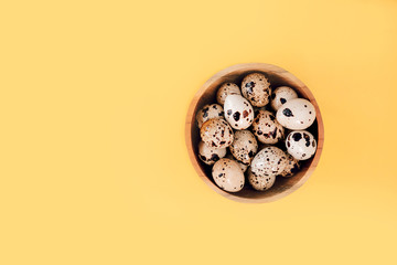 Quail eggs in basket on a yellow background. Easter concept, flay lay photo. Mockup, space for text.