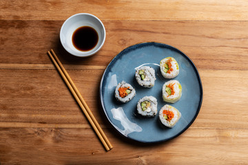 Stock photo ok Maki sushi on blue plate, soy and chopsticks. Asian gastronomic food composition on wooden table. Makis salmon and vegetables. © REFLEJAARTE 
