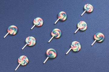 Lollipops are arranged symmetrically on a colored background. colorful candies