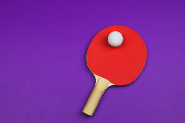 Red table tennis racket with a ball isolated on a colored background. sport equipment for ping pong