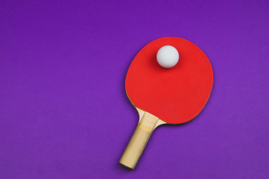 Red table tennis racket with a ball isolated on a colored background. sport equipment for ping pong