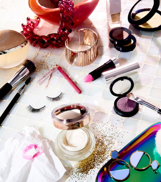 Open makeup containers and tools scattered over tile