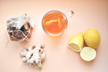 Herbal tea with ginger, lemon, honey and other herbs on a pink background.  The concept of a healthy calming and warming tea with a simple recipe, top view, text space, top view.