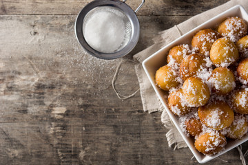 Carnival fritters or buñuelos de viento in bowl for holy week on wooden table. Top view. Copy space