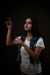 Fashion portrait of an young and attractive Indian Bengali brunette girl with tee shirt and blue western jacket in front of a black studio background. Indian fashion portrait and lifestyle.
