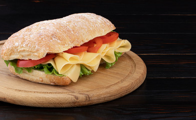 Ciabatta sandwich with lettuce and  cheese on wooden board with copy space