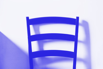 Blue wooden chair on white wall background. The back of the chair, detail. Minimal style