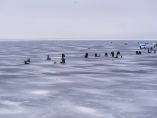 Foto op Aluminium large number of people and tents on ice of reservoir gathered on sunny winter day to do winter fishing. Hobby concept © galitsin