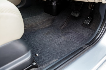 Clean car floor mats of black carpet with gas pedals and brakes in the workshop for the detailing...