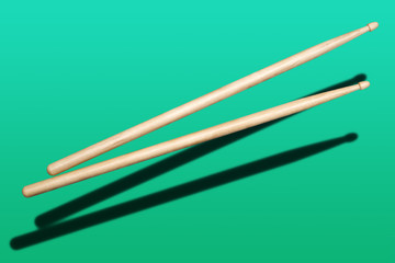 two wooden drumsticks on green background
